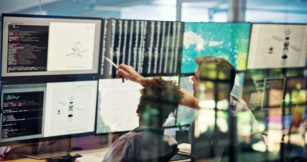 People looking at data on multiple screens.